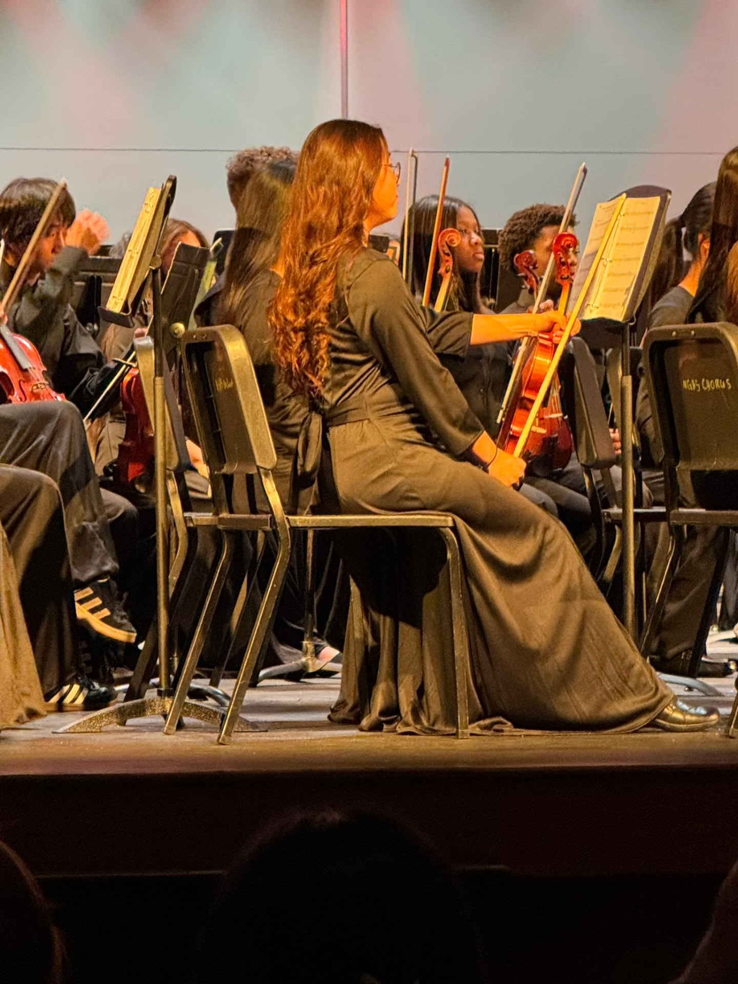 Haley performing violin with the school orchestra on stage